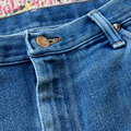 Close-up of blue denim jeans with a floral-patterned rug in the background