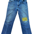 Blue jeans with a green patch on a white background