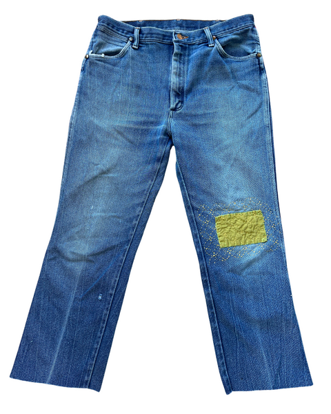 Blue jeans with a green patch on a white background