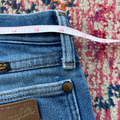 Blue jeans with a measuring tape on a colorful patterned rug