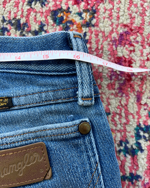 Blue jeans with a measuring tape on a colorful patterned rug