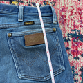 Blue jeans with a Wrangler label on a colorful patterned rug