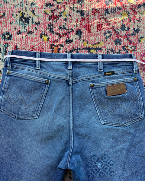 Blue jeans with a measuring tape on a patterned rug