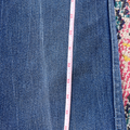 Close-up of blue denim fabric with a measuring tape on a colorful background