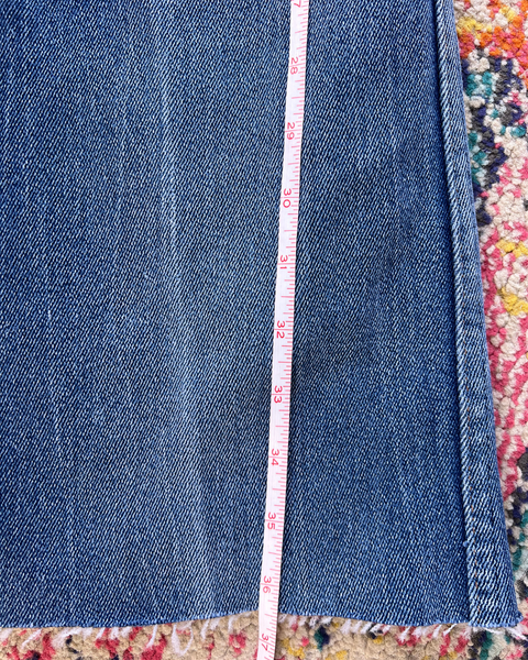 Close-up of blue denim fabric with a measuring tape on a colorful background