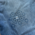 Close-up of blue denim fabric with a floral embroidery design.