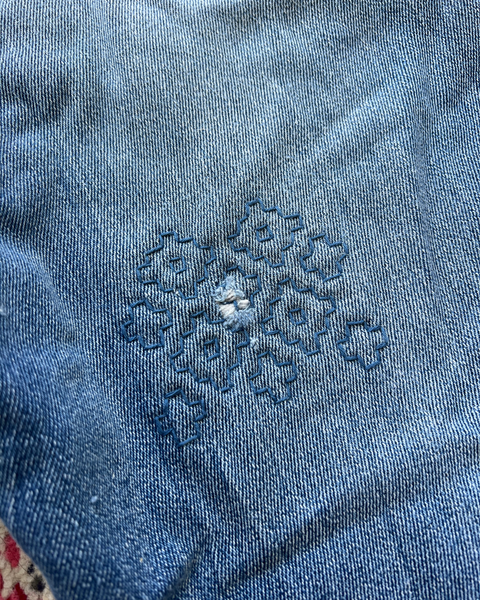 Close-up of blue denim fabric with a floral embroidery design.