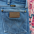 Close-up of Wrangler jeans with a visible brand logo on a patterned background