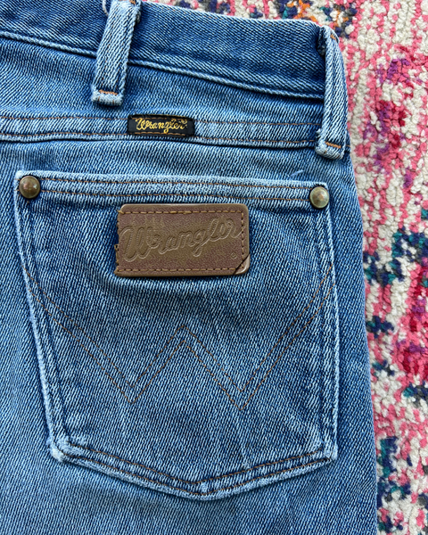 Close-up of Wrangler jeans with a visible brand logo on a patterned background