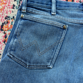 Close-up of blue jeans with a colorful patterned rug in the background