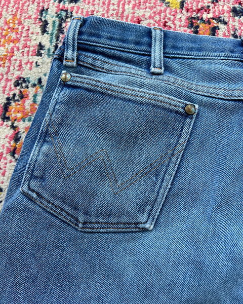 Close-up of blue jeans with a colorful patterned rug in the background