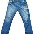 Blue jeans with distressing and embroidery on a white background