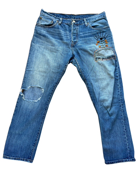 Blue jeans with distressing and embroidery on a white background