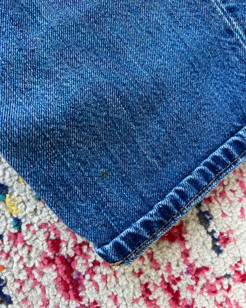 Close-up of blue denim fabric on a multicolored textured surface