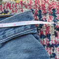 Measurements of a pair of blue jeans on a colorful patterned rug