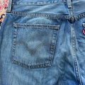 Close-up of blue Levi's jeans with a floral pattern in the background