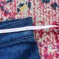 Close-up of a measuring tape on blue jeans with a colorful patterned rug underneath