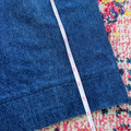 Blue denim fabric with a measuring tape on a colorful patterned surface
