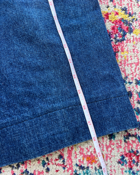 Blue denim fabric with a measuring tape on a colorful patterned surface