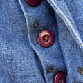 Close-up of a blue denim fabric with red buttons