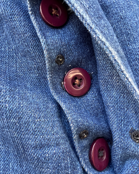 Close-up of a blue denim fabric with red buttons