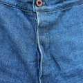 Close-up of blue denim fabric with a button and stitching detail.