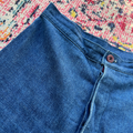 Close-up of blue jeans with a button on a colorful patterned rug
