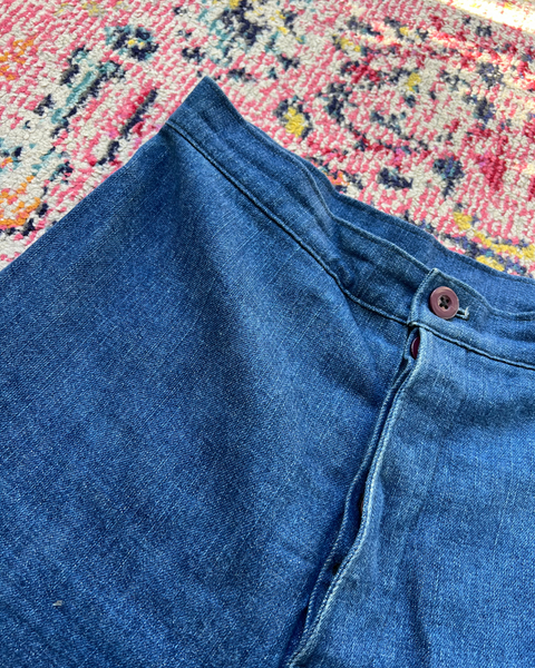 Close-up of blue jeans with a button on a colorful patterned rug