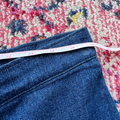 Blue jeans with a measuring tape on a floral-patterned rug