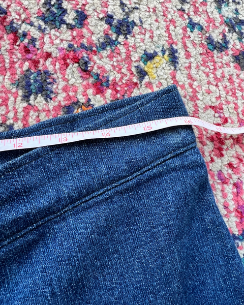Blue jeans with a measuring tape on a floral-patterned rug