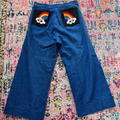 Blue pants with rainbow and cloud designs on a colorful patterned rug
