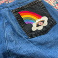 Blue denim fabric with a rainbow and cloud patch on a colorful background