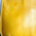 Close-up of a yellow leather bag with visible wear and tear.