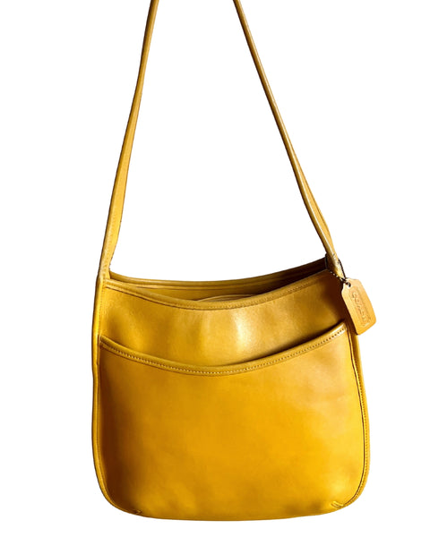 Yellow leather handbag with a strap on a white background